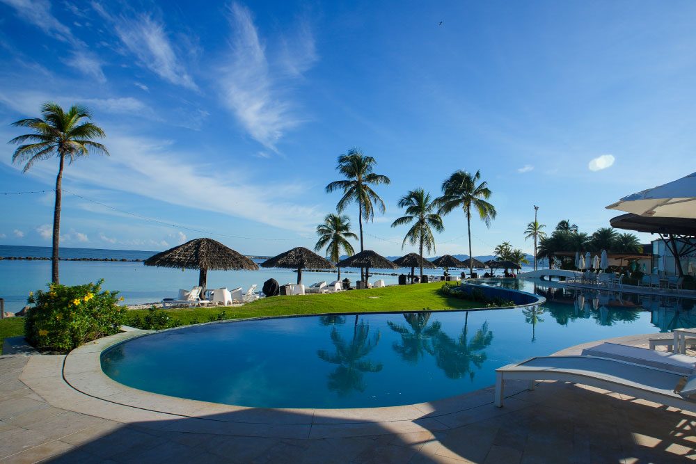 Piscina con sombrillas de palma y vista al mar en el Blu Beach Club de Playa Escondida