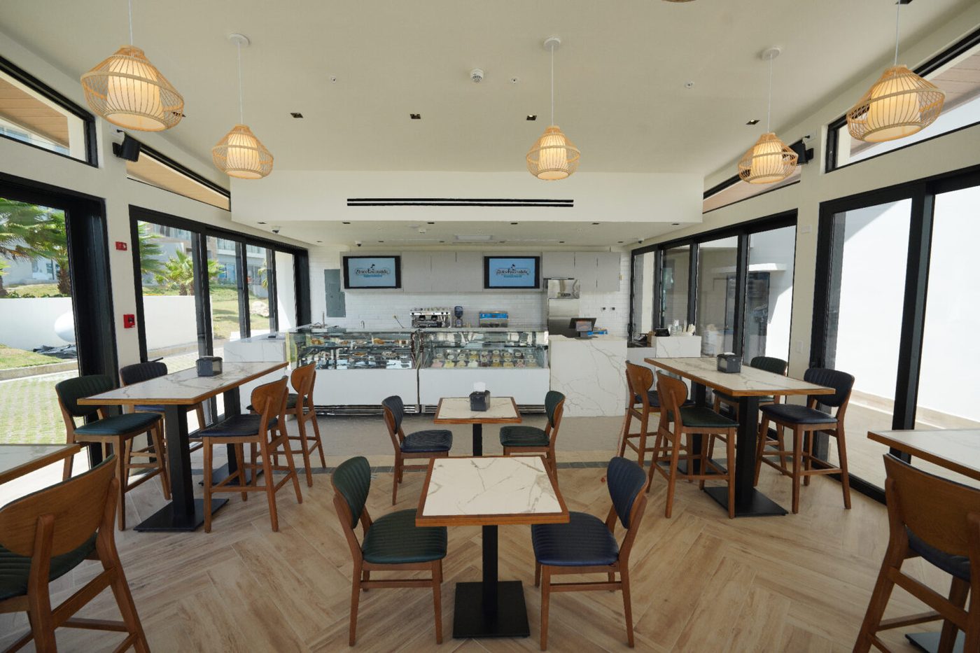 Interior luminoso de Dolce Escondida, la gelatería de Playa Escondida, con mesas de madera y ventanales