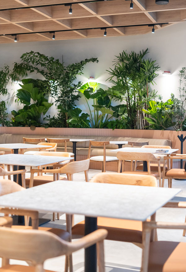 Salón de Botanica Pizza con mesas de mármol y muro de plantas