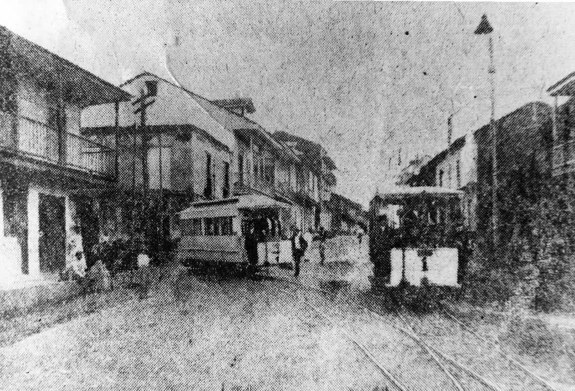 Fotografía antigua de una calle de la ciudad de Panamá con tranvías y casas de madera