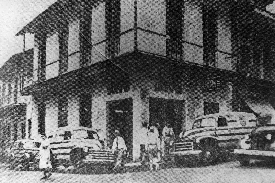 Fotografía antigua en blanco y negro del edificio de Café Durán en Calle 16, con autos de época en la esquina