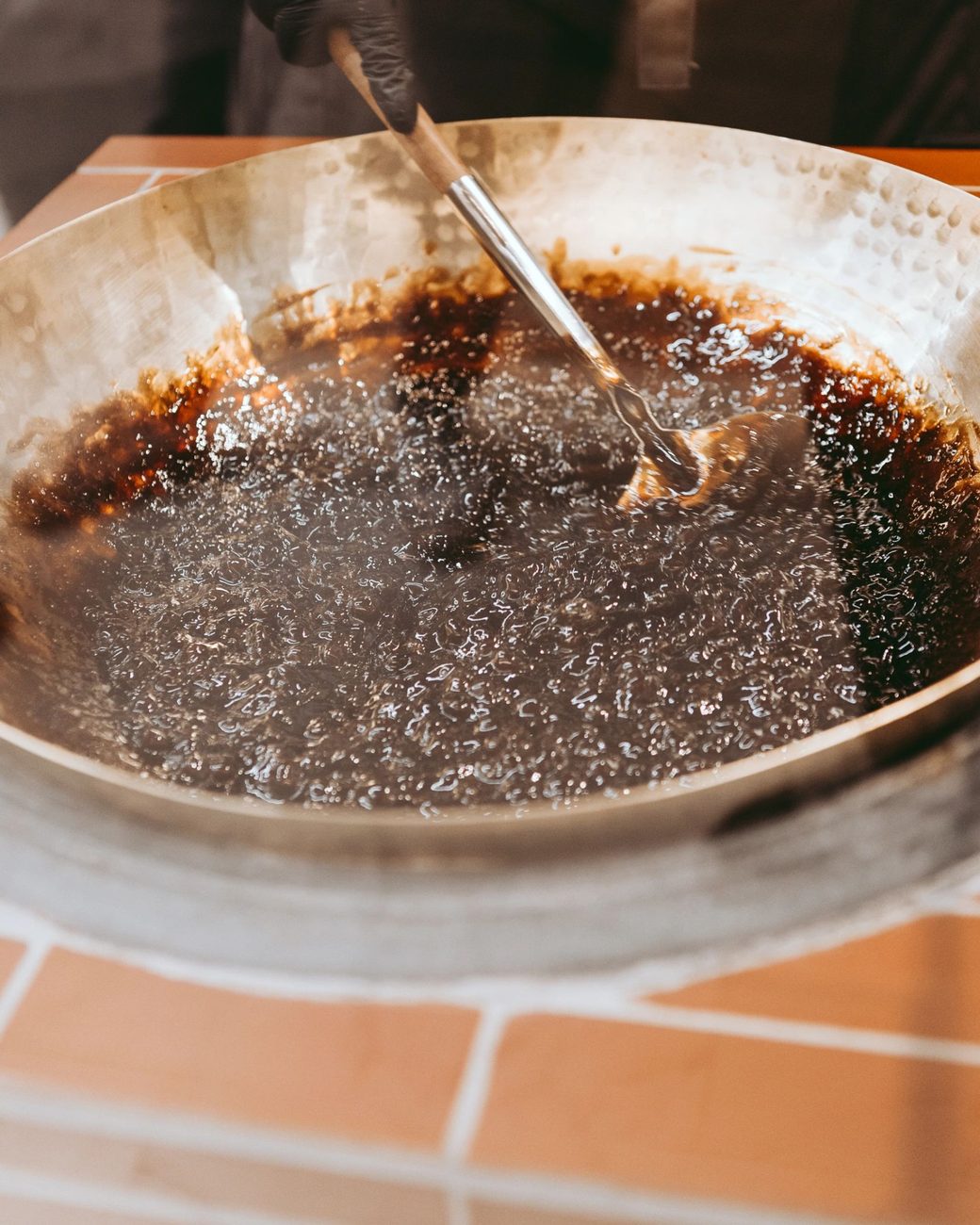 Perlas de tapioca burbujeando en jarabe de azúcar morena dentro de un wok mientras se revuelven