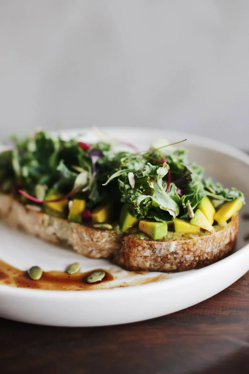 Avo toast sobre pan campesino de masa madre con kale, semillas y granada