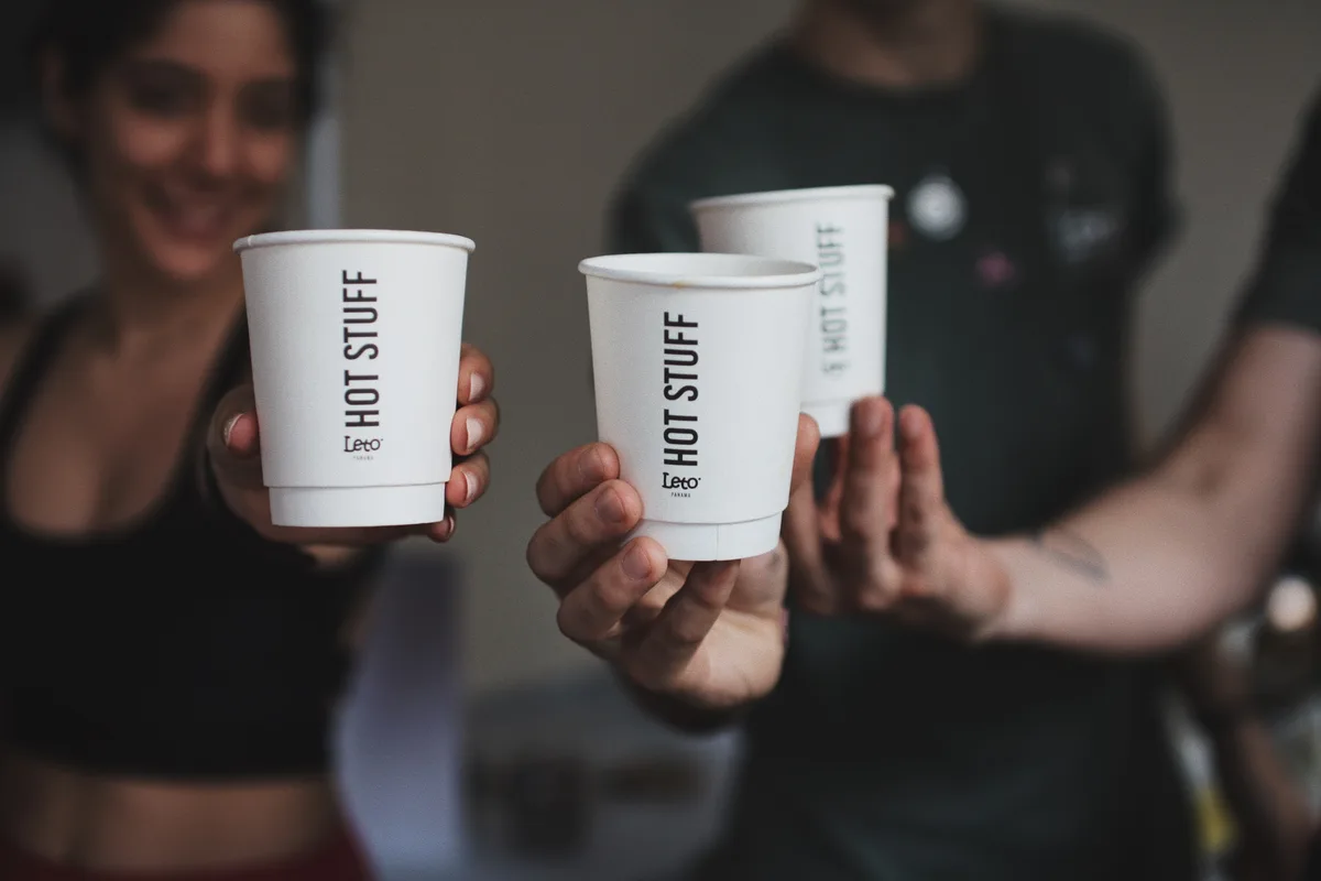 Clientes brindando con vasos de café de Leto Coffee