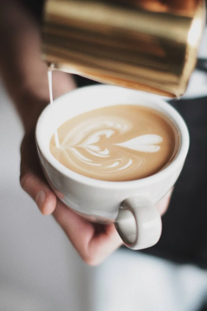 Barista de Leto Coffee vertiendo leche texturizada sobre un latte con arte en forma de corazón
