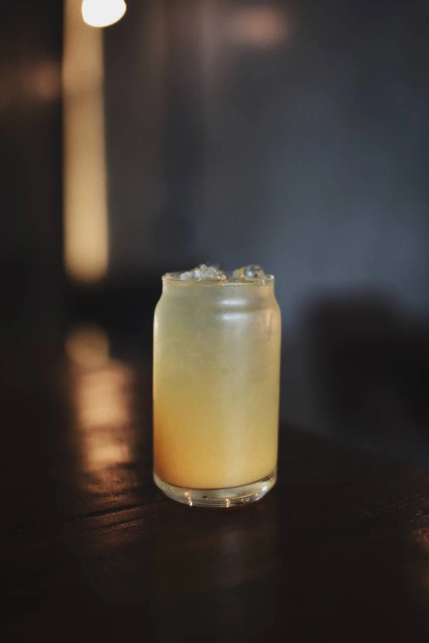 Bebida fría de cítricos con hielo servida en vaso de vidrio