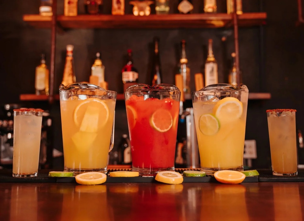 Tres pitchers de margarita con escarchado de chile en la barra
