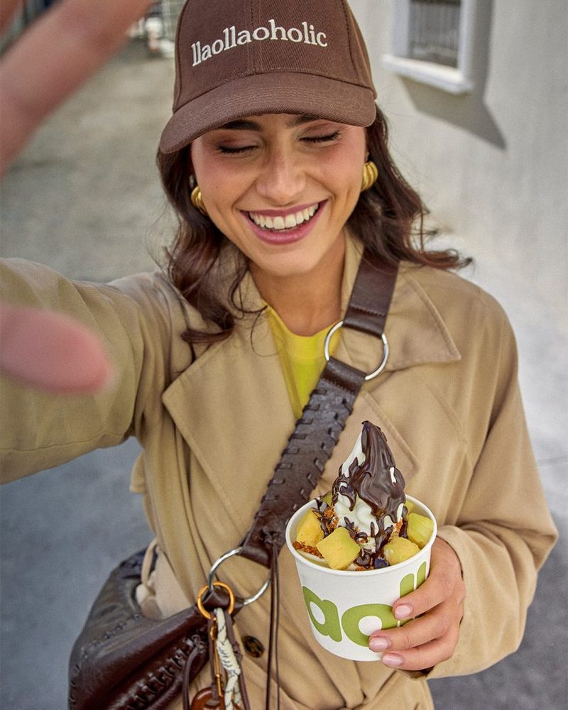Chica sonriente con una tarrina llaollao con salsa de chocolate