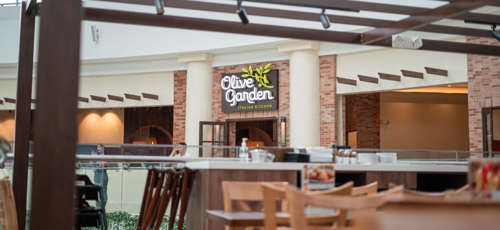 Fachada de Olive Garden en Altaplaza Mall con terraza de mesas de madera