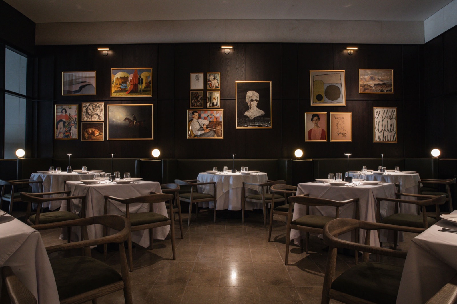 Comedor de Benny's con paredes oscuras, cuadros enmarcados y mesas con mantel blanco