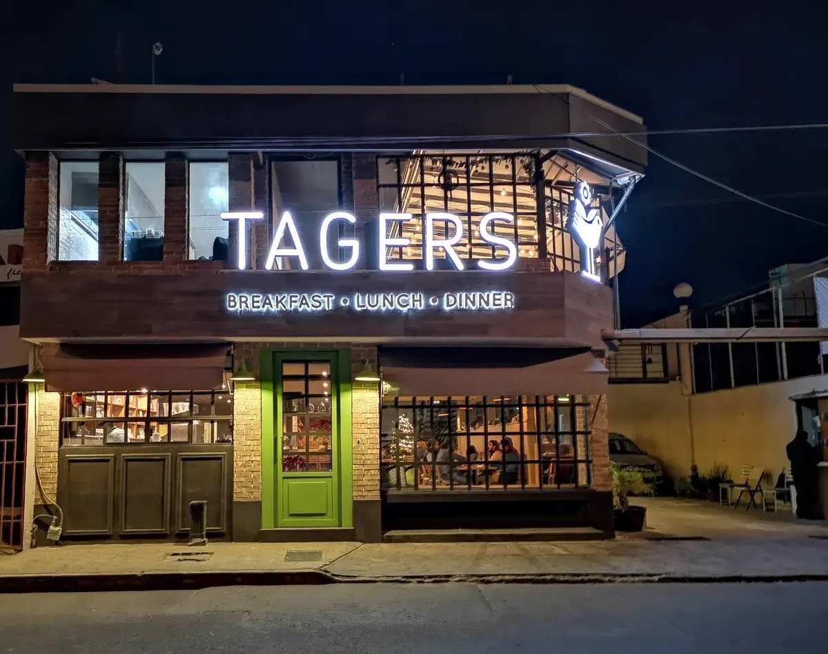 Fachada iluminada de noche de Tagers 5 Sur en Puebla, con su letrero Breakfast, Lunch, Dinner