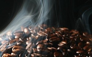 Granos de café recién tostados humeando