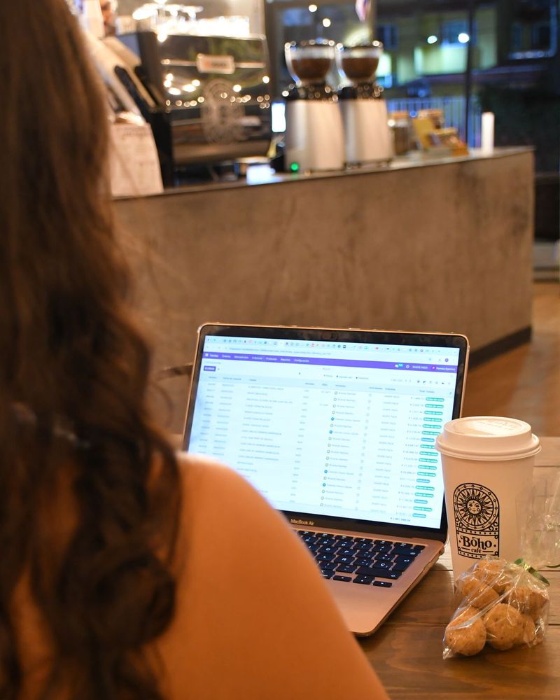 Persona trabajando en su laptop con un café de Boho Cafe frente a la barra
