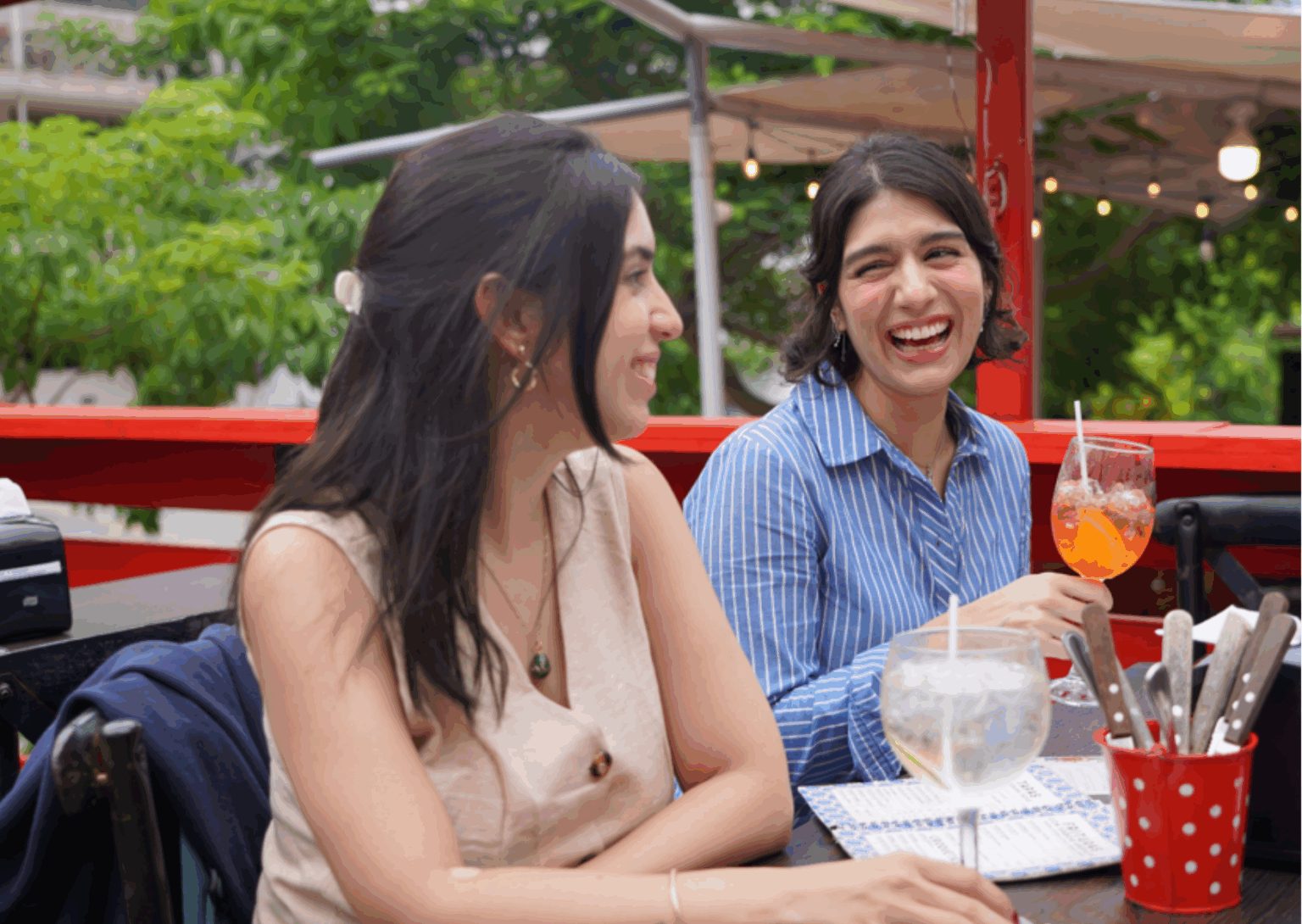 Dos amigas riendo con copas de vino y sangría en la terraza de La Malagueña