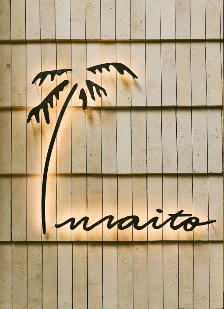 Letrero iluminado de Maito con su palmera sobre una pared de madera
