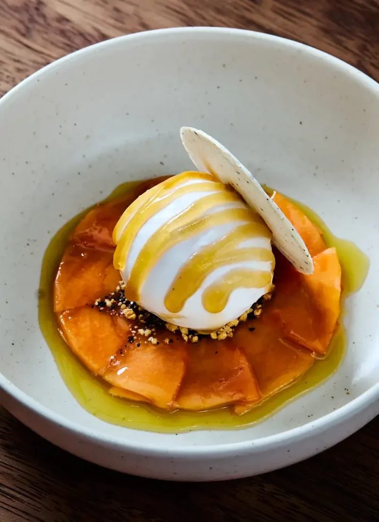 Postre de Maito con helado, papaya y caramelo servido en plato hondo