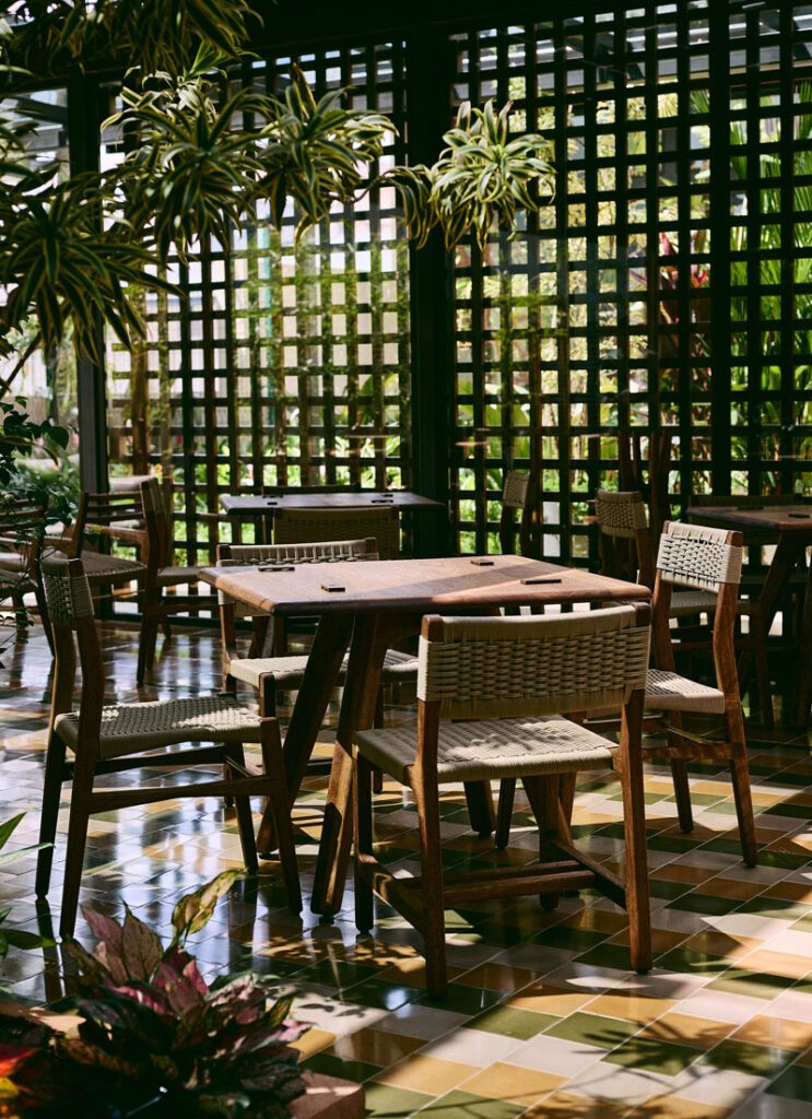 Terraza de Maito con mesas de madera bajo una celosía y vegetación